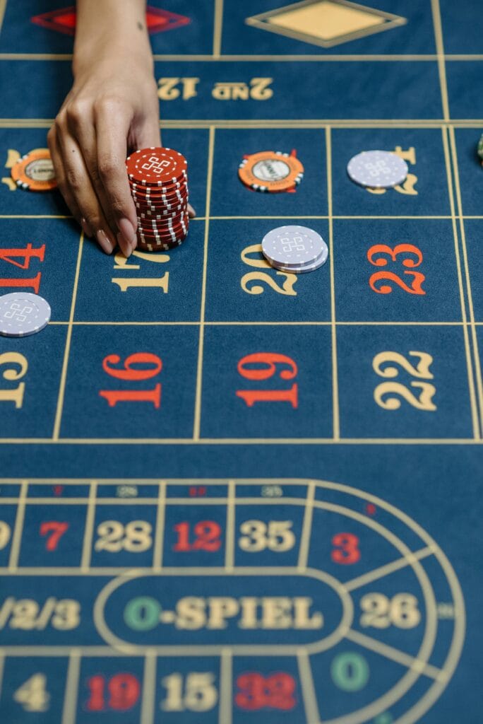 Close-up of a hand placing chips on a casino roulette table during a game.